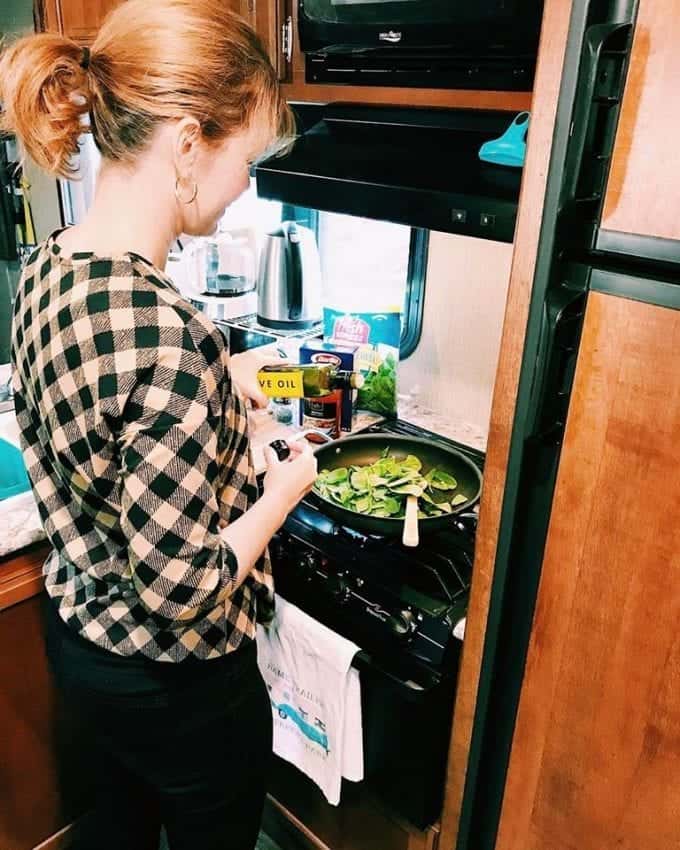 Woman cooking spinach in a skillet, one of her essential RV kitchen items.
