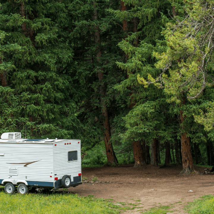 RV with solar panels on roof parked in wooded area