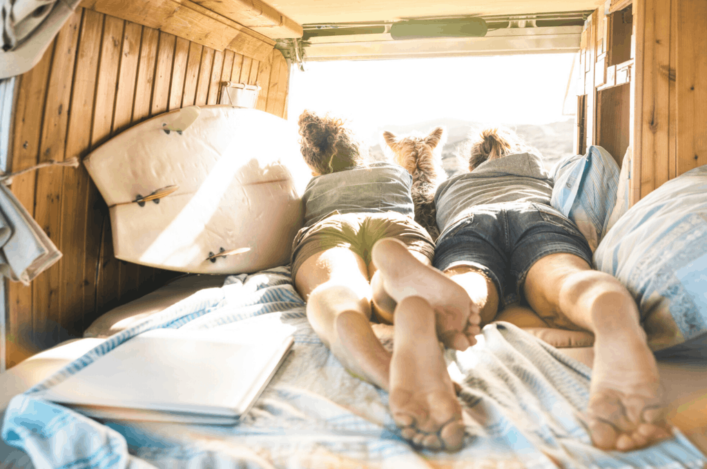Two people and dog on bed in camper van