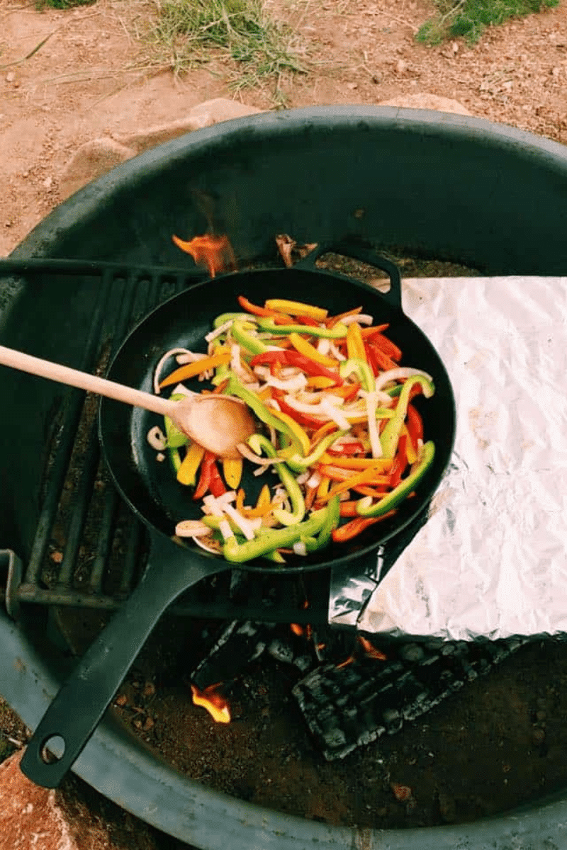 Cast iron pot filled with peppers over campfire
